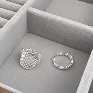Close-up detail of silver mesh geometric rings and braided band set displayed neatly.