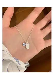 Close up of sweet blue heart and tag pendant silver necklace, delicate trendy clavicle chain.