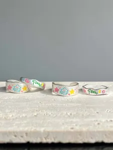 Close-up of colorful painted graffiti open rings with cute dinosaur and tree motifs.