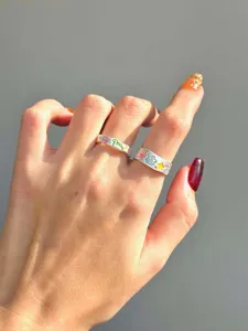 Close-up detail of silver open ring featuring colorful painted dinosaur and doll graffiti art.
