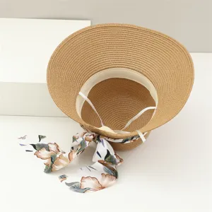 Primer plano detallado del sombrero de paja para mujer con cinta floral y ala ancha elegante.