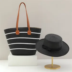 Sac cabas en paille rayé noir et blanc et chapeau de soleil noir pour vacances plage.