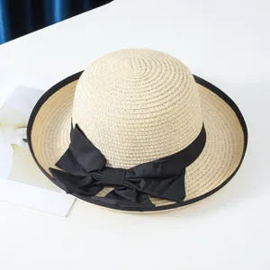 Detalle de primer plano del sombrero de paja de verano para mujer con lazo negro clásico.