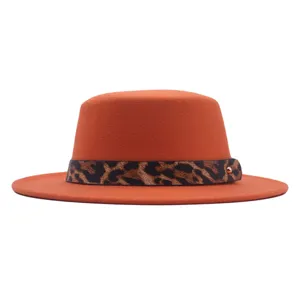 Vue de détail en gros plan du chapeau plat en laine orange avec sangle imprimé léopard.