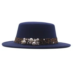 Sombrero plano de fieltro azul marino con cinta de leopardo, perlas y flores decorativas.