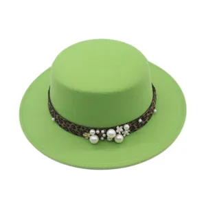 Detalle del sombrero plano verde con banda de leopardo y elegantes adornos de perlas y flores.