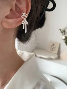 Detaillierte Nahaufnahme einer stilvollen silbernen Schleifen-Ohrmanschette für Damen.