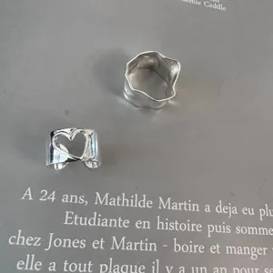 Silver minimalist hollow heart and irregular geometric stacking rings detail view, stylish chic.