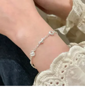 Delicate silver croissant and heart chain bracelet, trendy niche design women jewelry detail.