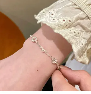 Close-up detail of silver creative bread heart charm chain bracelet worn on wrist elegantly.