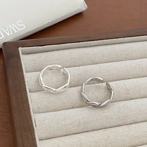 Detailed shot of twisted silver open rings on beige jewelry tray, retro street style ring.