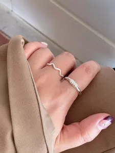 Silver ring detailed view showcasing the unique wave and twisted band design on finger.