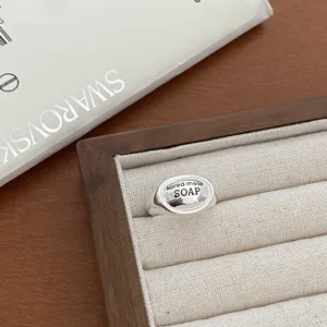 Close-up of a silver geometric signet ring with engraved text detail in velvet tray.