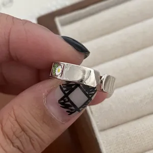Detail of versatile silver open ring with enamel daisy flower, retro hip hop style jewelry piece.
