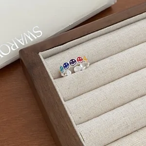 Silver tone metal open ring featuring cute colorful smiley faces, stylish detail shot.