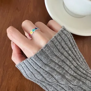 Detail shot of a trendy colorful smiley face silver ring worn on index finger stylish.