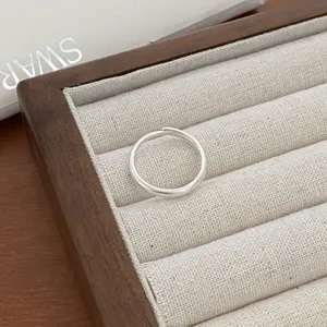 Minimalist silver open ring detail shot displayed neatly in a beige linen jewelry tray.