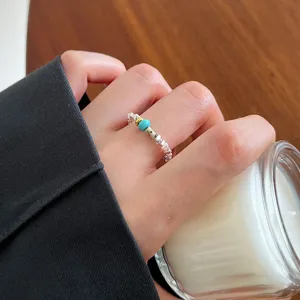 Close-up detail shot of silver textured open ring featuring turquoise and gold bead.