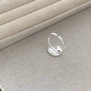 Close-up view of minimalist silver geometric open ring displayed on textured jewelry tray.