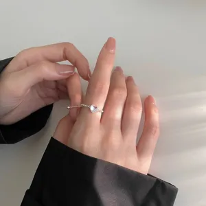 Close-up detail of delicate silver heart chain ring, elegant hand wear showcase style.
