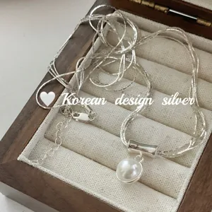 Vue détaillée d'un collier pendentif perle argenté chic, élégant bijou de clavnette tendance.