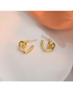 Vue rapprochée des boucles d'oreilles clous dorées en forme de cœur avec détails métalliques.