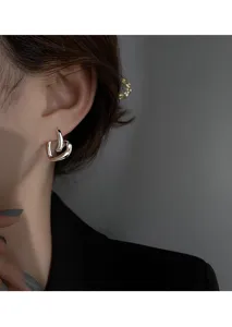 Gros plan sur les boucles d'oreilles en metal en forme de cœur entrelace, detail elegant.