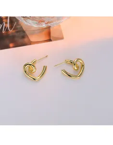Gros plan de boucles d'oreilles cœur torsadées dorées, style de bijoux minimaliste moderne.