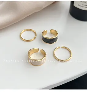 Set van vier geometrische emaille ringen met strakke gouden banden en chique zwart-witte.