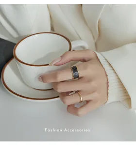 Close-up van een elegante brede zwarte gestructureerde ring en een slanke gouden ring op hand.