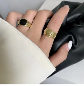 Gros plan de bagues géométriques et émaillées noires portées à la main, bijoux style rétro.