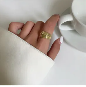 Vue détaillée d'une bague dorée multicouche élégante portée à la main, design minimaliste.