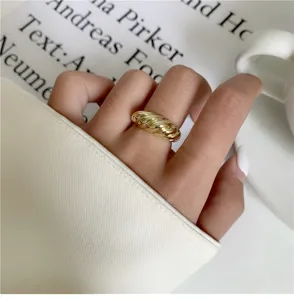 Gros plan d'une élégante bague torsadée dorée portée sur une main, superbe design géométrique.