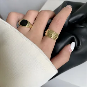 Bagues dorées à rayures géométriques et émail noir portées à la main, bijoux tendance.