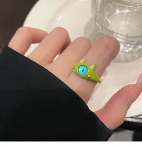 Detailed close-up view of the cute green little monster ring with blue cat-eye stone feature.