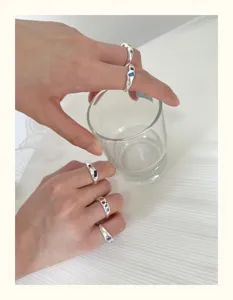 Detailaufnahme silberner stapelbarer Ringe mit bunten Zirkoniasteinen am Finger präsentiert.