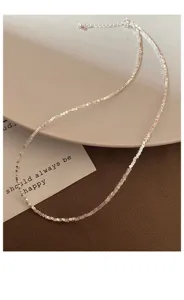 Vue détaillée du collier de perles géométriques argentées, texture de chaîne délicate.