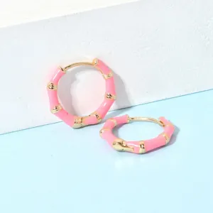 Nahaufnahme der rosa Bambus-Ohrringe mit goldenen Gliedern und glatter Lackoberfläche.