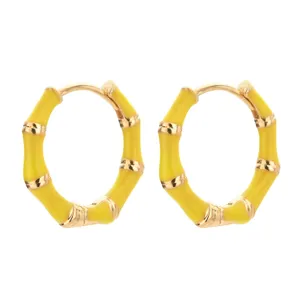 Nahaufnahme gelber Bambus-Creolen, elegantes Emaille-Metall-Schmuck-Design im Detail.