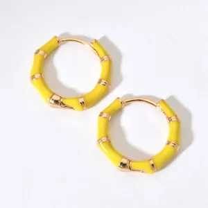 Nahaufnahme detailreicher gelber Bambus-Creolen mit eleganten goldfarbenen Metallakzenten.