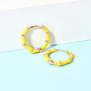 Nahaufnahme von trendigen gelben Bambus-Creolen, glänzendes Finish, elegantes Modeaccessoire.