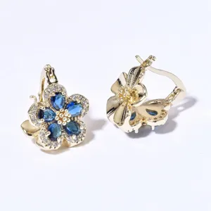 Nahaufnahme von goldenen Blumenohrringen mit blauen Zirkonia und Steinen im Detail.