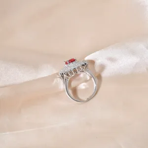 Primo piano dettagliato dell'elegante anello con pietra rossa ovale e diamanti scintillanti.