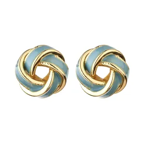 Closeup of blue enamel gold knot stud earrings, detailed geometric design, elegant jewelry detail.