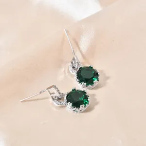 Primo piano dettagliato di lussuosi orecchini con pietra verde e luminoso alone in pavè.