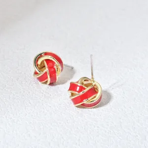 Detailed close-up of red and gold knot stud earrings, showcasing delicate enamel craftsmanship.