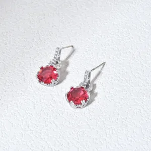 Primo piano di eleganti orecchini pendenti argentati con pietre rosse e zirconi scintillanti.