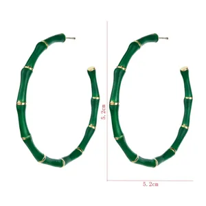 Vue détaillée de boucles d'oreilles créoles en bambou vert mesurant 5,2 cm avec détails dorés.