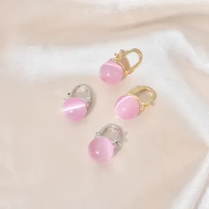 Nahaufnahme von rosa Katzenauge Ohrringen, goldene und silberne Metallcreolen Details.