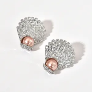 Close-up detail of gleaming shell shaped earrings paved with sparkling cubic zirconia and pink pearl.